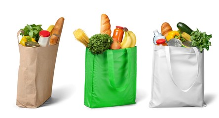 Shopping bags with groceries on white