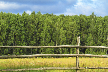 Old fence made of wood in countryside. Beautiful summer landscape with forest and mountain. Rustic lifestyle concept