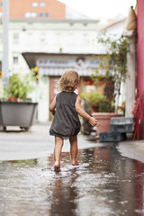 Kleines Mädchen läuft durch Wasserpfütze.  Happy child girl running trough water.
