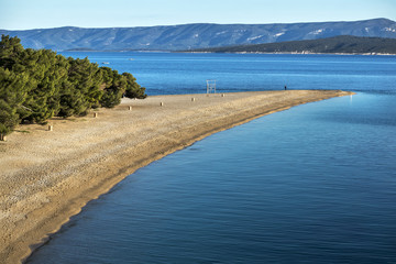 Sunset on pebble beach Golden cape (Zlatni rat) is one of most famous beach in Croatia, on south side of island Brac near town Bol