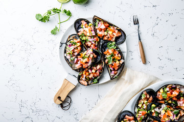 PERUVIAN FOOD. Choros a la chalaca. Big mussels, choros zapatos seasoned with purple onion, tomatoes, corn and lemon. Top view, white background. Traditional peruvian dish