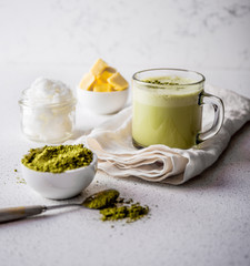 BULLETPROOF MATCHA. Ketogenic keto diet hot drink. Tea matcha blended with coconut oil and butter. Cup of bulletproof matcha and ingredients on white background