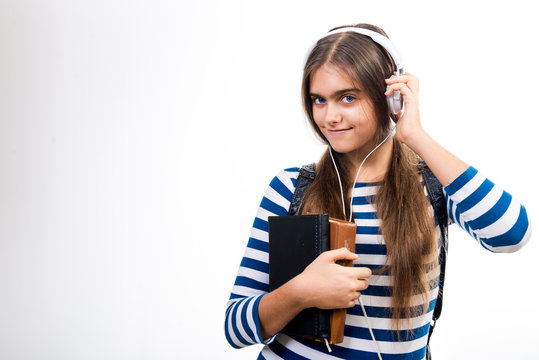 Girl in headphones. The girl listens to music on headphones. Modern teen girl goes to school. Girl student on white background. Schoolgirl with books and headphones on a white background

