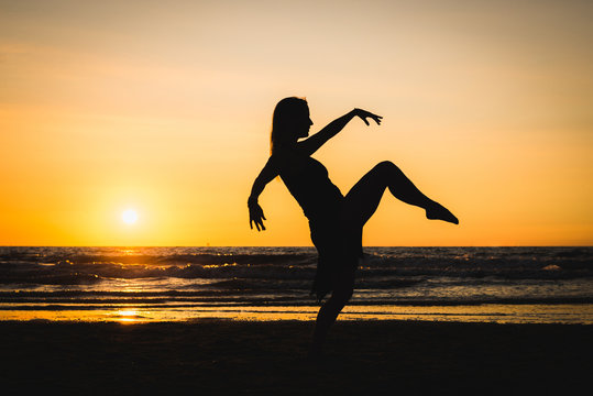 Silhouette of a happy dancer girl at sunset