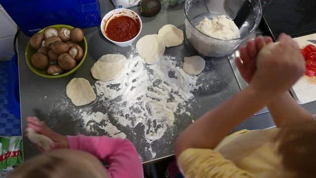 Children cut the dough flat for small pizzas