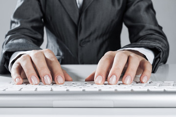 Closeup of businesswoman hand typing on keyboard with mouse on w