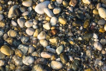 pebble stones on the sea beach, the rolling waves of the sea with foam