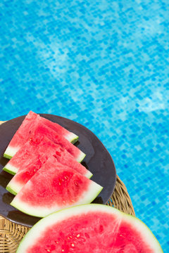 Ripe Juicy Seedless Watermelon Cut in Slices Wedges on Plate on Rattan Table by Swimming Pool. Sunlight. Seaside Vacation Relaxation Wanderlust Summer Vibes. Lifestyle. Poster