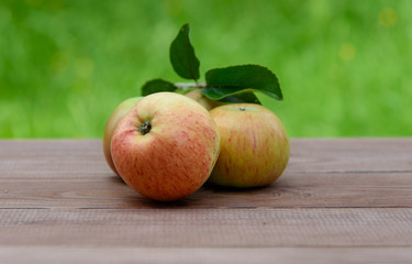Juicy apples on a wooden table on a green background