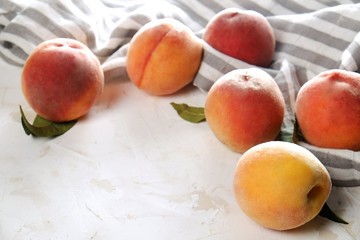 Bunch of ripe organic peaches in pile on white concrete surface table. Local produce harvest heap on vintage plaster countertop, napkin. Clean eating concept. Copy space background, top view, close up