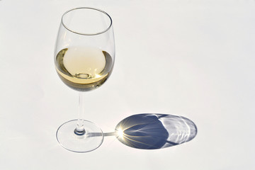 Glas Weißwein im Sonnenlicht mit Schattenreflexionseffekt und einem leeren Kopienraumhintergrund