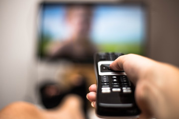 Hand Holding Use Remote Control and Watching TV in House on a colorful flatscreen modern