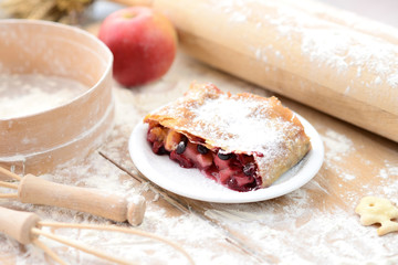 strudel (roll strudel) with apple and currant on a wooden board with flour