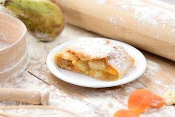 strudel (roll strudel) with apple and apricot on a wooden board with flour