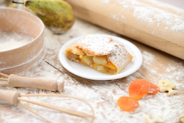 strudel (roll strudel) with apple and apricot on a wooden board with flour