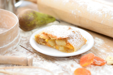 strudel (roll strudel) with apple and apricot on a wooden board with flour