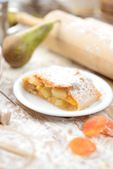 strudel (roll strudel) with apple and apricot on a wooden board with flour