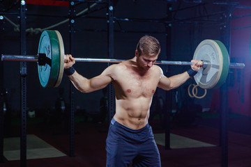 Fototapeta na wymiar Portrait of a handsome athlete . Athlete raises the barbell over your head. shots in the dark tone. Cross style fit, deadlift