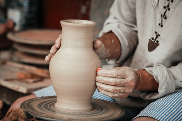 Fototapeta na wymiar hands of a potter, creating an earthen jar on the circle 