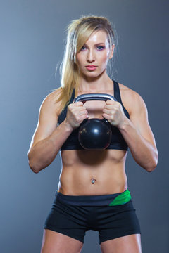 Fit woman doing squats with kettlebell in sport club. gym