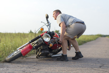 A man lifts a motorcycle that fell after an accident