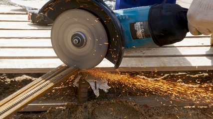 Angle grinder, which cuts the armature.Man cuts armature by grinder