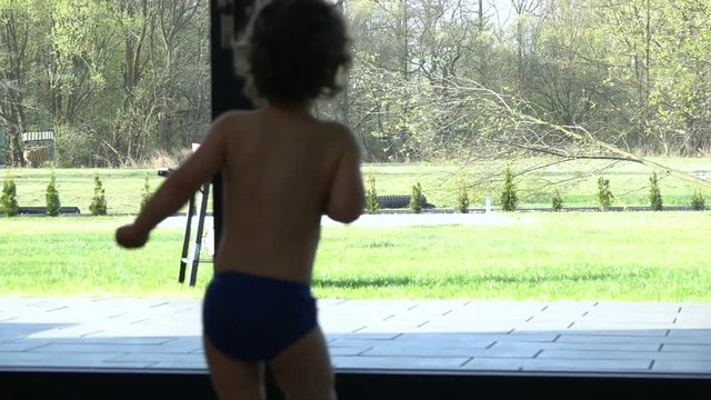 Baby boy running to the window and wearing only underwear, slow motion shot at 240fps
