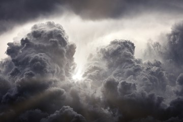 Sun rays breaking through the dark clouds. Clouds background. Dramatic grey clouds