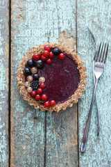 Raw vegan pie with berry jam and organic currants on blue background