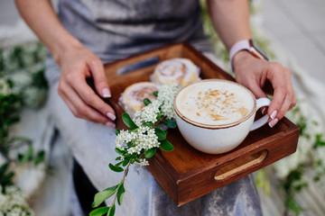 Coffee and cinnabon on a tray with flowers.