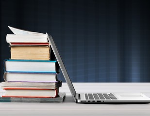 Stack of books with laptop on table