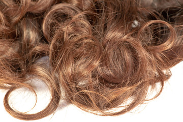 A set of hair extensions of reddish brunette curly hair on a beauty shop table