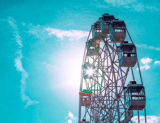 Colorful ferris wheel of the amusement park in the blue sky background