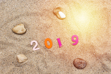 colorful wooden numbers forming the number 2019 on sand and stones all around , For the new year 2019