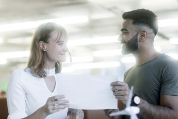 Junges Paar im Büro stehend mit Protokoll