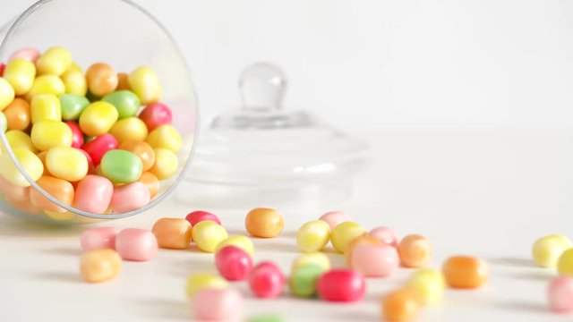 food, confectionery and sweets eating concept - close up of scattered candy drops and jar on table