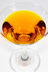 Halloween inspired orange color cocktail in a clear glass sitting on a white table waiting to be enjoyed.