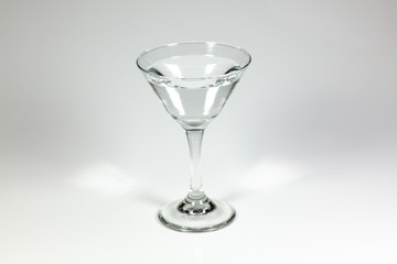 Halloween inspired clear color cocktail in a clear glass sitting on a white table waiting to be enjoyed.