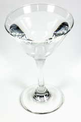 Halloween inspired clear color cocktail in a clear glass sitting on a white table waiting to be enjoyed.