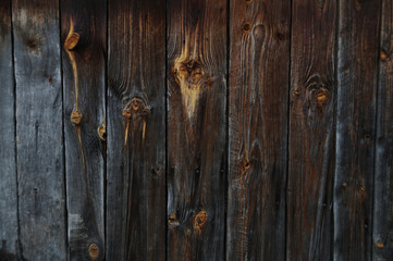 A wall of a wooden building, boards blackened with old age.