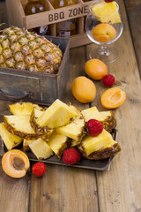 ripe tropical fruits for juice and cocktail at a party. A box of beer and a wooden background. Vintage photo. Copy space,