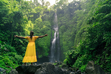 Fototapeta premium Woman in yellow dress at the Sekumpul waterfalls in jungles on Bali island, Indonesia