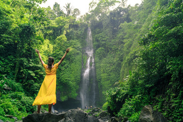 beautiful woman in yellow dress near waterfall wall