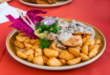 Roast chicken steak in white mushroom sauce with fried potato wedges