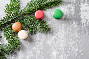 Fototapeta na wymiar Merry Christmas card. Variety of sweet macaroons and fir branches on a gray vintage background. flat lay, top view. New year mood