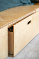 Furniture made of plywood. Retractable floor box, with a hole for the hand. Soft focus and shallow depth of field. Vertically.