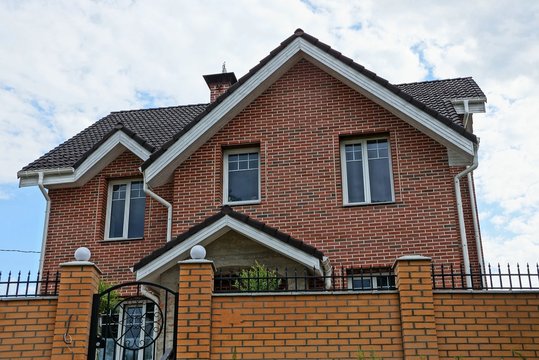 large private brown brick house with windows behind the fence