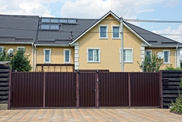 long brown metal gates and a closed gate on the street on the sidewalk in front of a large private...