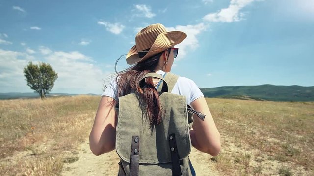 Female European traveler with backpack on the trail of dried field at trekking lifestyle trip