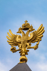Golden Russian coat of arms on a blue sky background. Coat of arms of Russia is the official state symbol of the Russian Federation and Russian Empire in history.